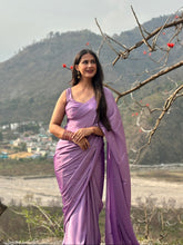 Woman in a purple saree standing outdoors with mountains in the background
