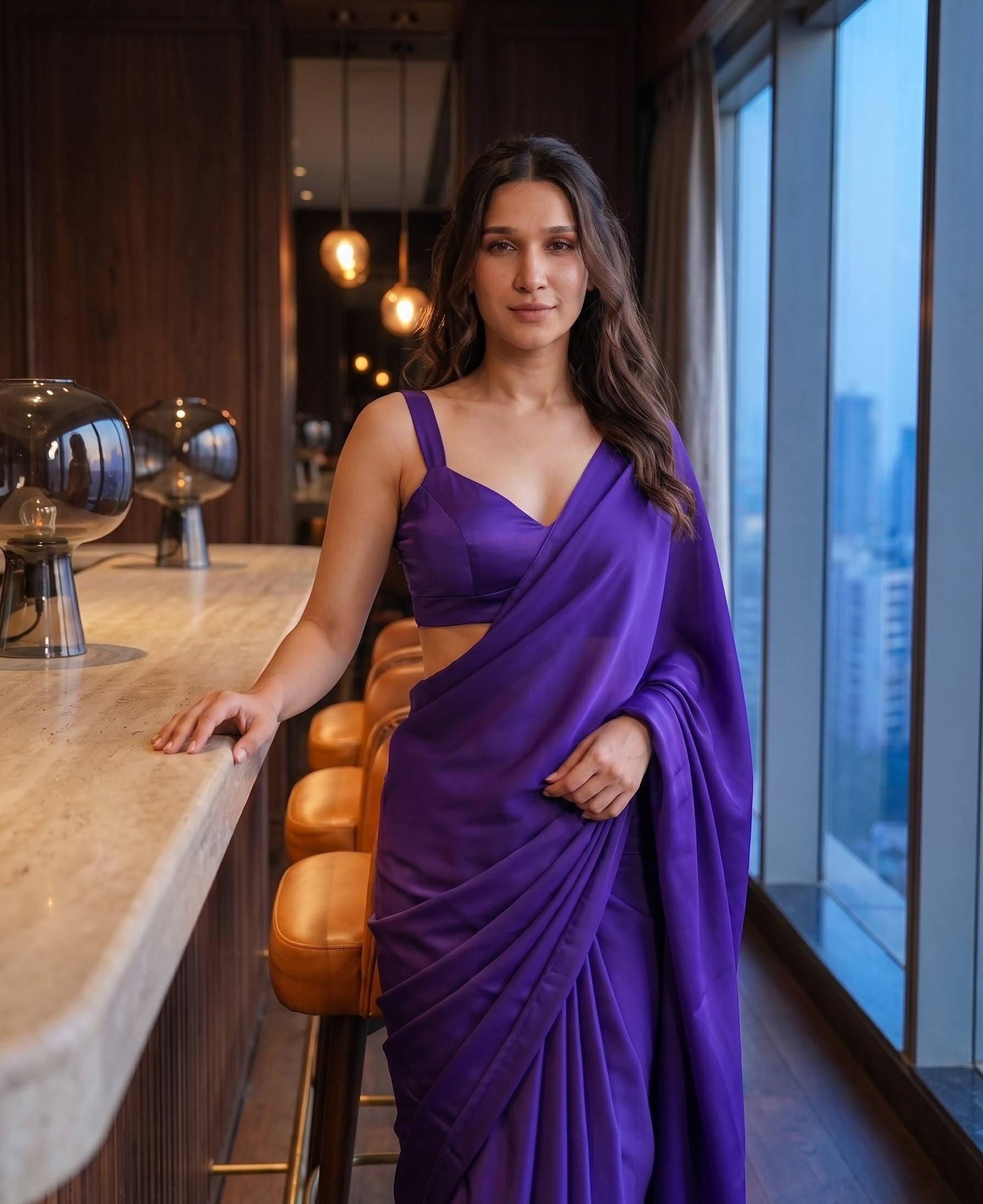 Woman standing in the Orchid Noir purple chiffon saree at a lounge bar