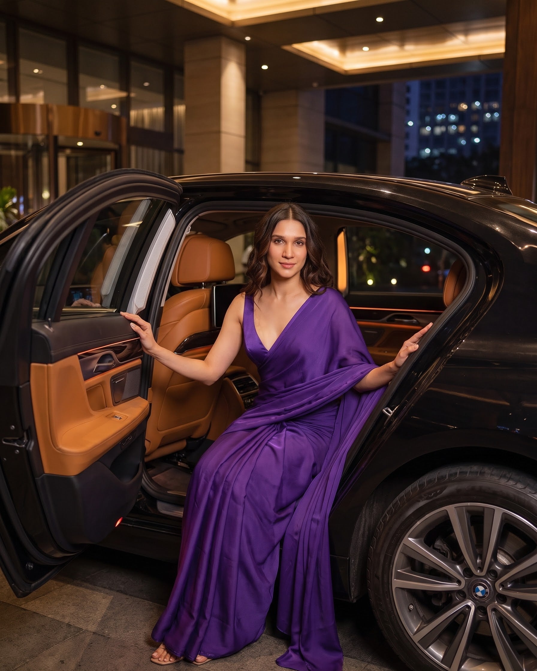 Woman pausing by a car door in the Orchid Noir purple chiffon saree