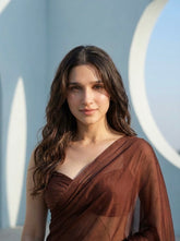 Close-up portrait of woman in Cocoa Mirage brown chiffon saree against a white architectural backdrop